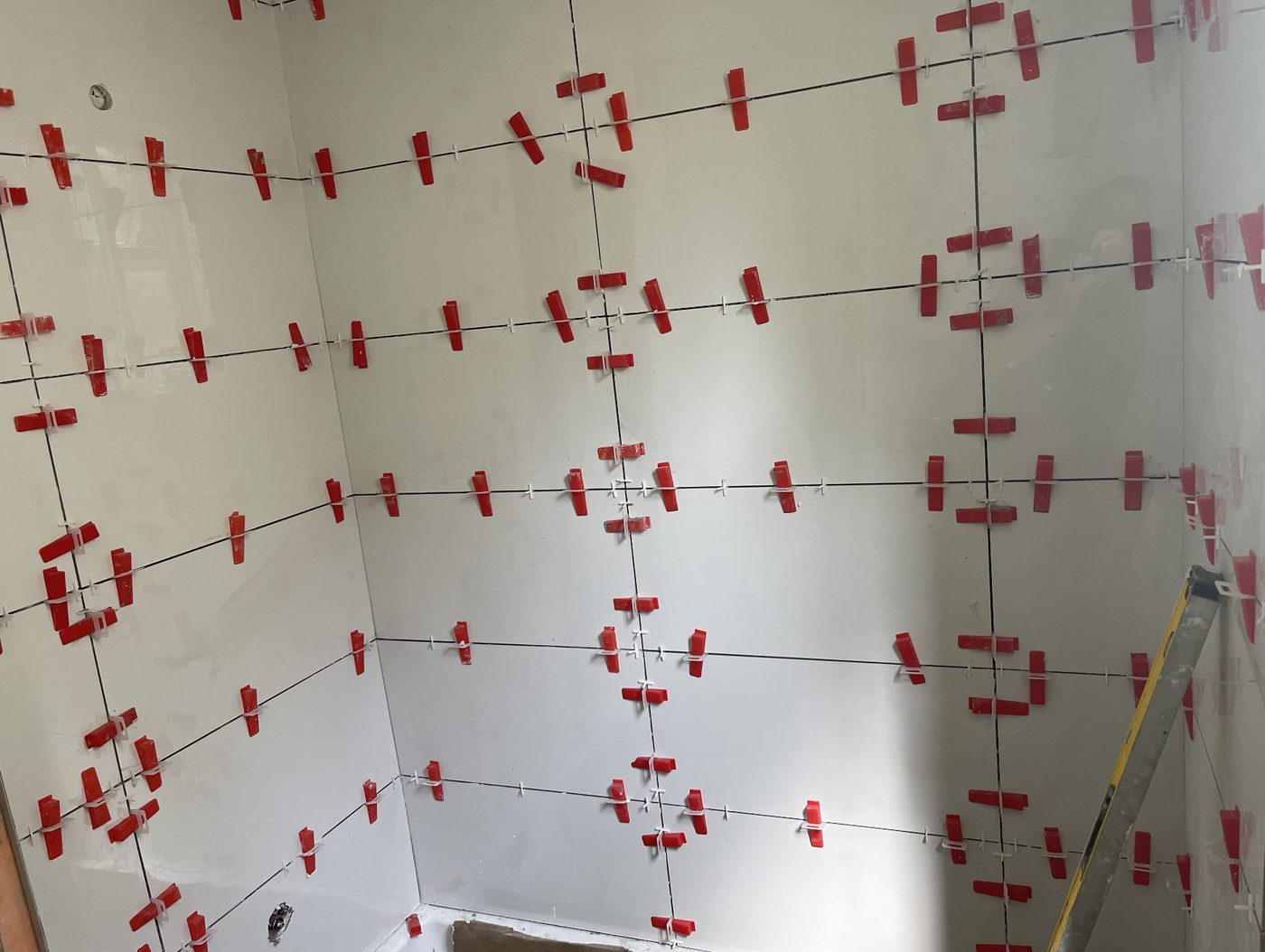 Large-format polished shower wall tile with levelling clips, bathroom renovation in North Vancouver